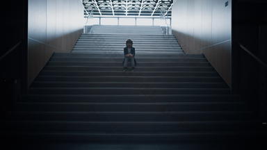 不开心小学生坐着楼梯关闭孤独的恶霸受害者隐藏